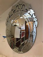 Full frontal view of large oval etched mirror mounted on wall