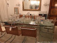 Set of wicker chairs arranged around glass top table with crystal serveware