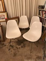 Front view of all four white resin chairs grouped together on carpet.