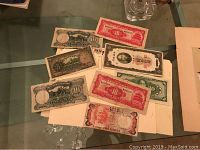 Glass tabletop view of multiple currency notes: two Sierra Leone and several Chinese yuan bills