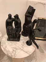 Group shot of three black figurative sculptures on marble side table