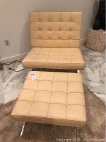 Front view of chair and ottoman on marble floor showing tufted leather upholstery and chrome X-frame.