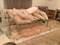 Set of 8 cream colored throw pillows (3 shag, 5 regular) placed on glass table and floor. Two cream-colored shag rugs, one smaller genuine lambskin rug (45x78) and one larger rug underneath.