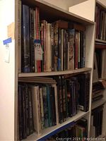 Two shelves filled with hardcover and paperback books on various subjects including history, art, California, Canada, and astronomy. Books vary in condition and size.