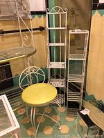 Photo showing two white metal stands and a white metal vanity chair with yellow padded seat together on hex tile floor. Items show signs of wear including scratches and soiling.
