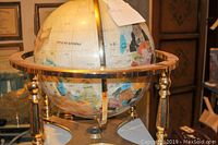 Full view of the globe on metal stand showing overall appearance and damage.