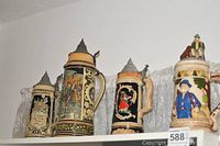 Four beer steins arranged on a shelf showing front side and lids