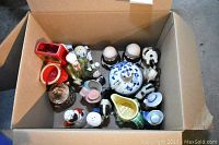 Top view of a box filled with assorted ceramic figurines including pitchers and animal figures