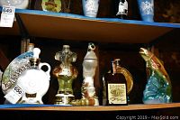 Shelf display of seven collectible liquor bottles including Jim Beam Regal China Series bottles and an E.G. Booze bottle.