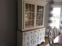 Front view showing the two-piece china cabinet with glass doors in the top section and wooden drawers and cabinets below.