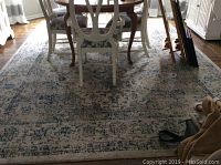 Full view of the Safavieh area rug under a dining table showing the size and pattern.