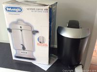 DeLonghi Ultimate Coffee Urn box with the urn placed beside it, showing front on the box and urn design