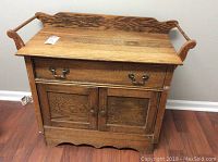 Front view of oak cabinet showing drawer and double doors with brass and wooden knobs
