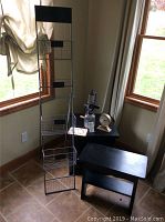 Photo showing black wire magazine rack next to black wooden storage cube, vintage manual grinder, gold-tone desk clock, and bar sign.