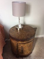Full lamp on top of round wooden side table with visible wear