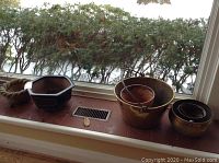 Wide view showing several plant containers and a live green leafy plant on the window sill.