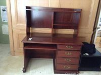 Front view of the faux wood desk with hutch, showing drawers, door, and keyboard tray.