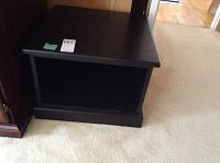 Front view of black faux wood stand showing open compartment and top surface.