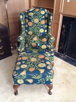 Front view of floral wing chair with matching ottoman in front.