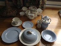 Overview photo showing Ridgway blue glazed dishes and tea set, Johnson Bros floral cups and plates stacked, and a blue teapot with creamer and covered dish.