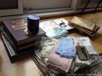 Photo showing stack of books including 'Loyal She Remains' and some linen pieces and coasters on the floor.