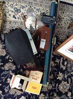 Overhead shot showing the projector screen stand, various camera equipment cases, Kodak film box, and manual.