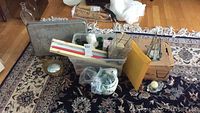 Overview of the lot on a patterned rug including boxes, bucket, candles, candle holders and a small mirror
