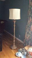 Full view of the ornate standing lamp with a fabric shade in a room corner.