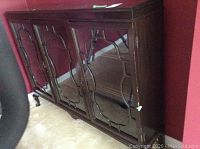 Front view of vintage wooden display cabinet with three glass doors and decorative wooden mullions. Visible chips on finish near edges and legs.
