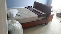 Overall assembled sleigh bed in bedroom, showing headboard, footboard, mattress, comforter, and pillow
