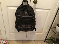 Front view of black and gray Metro Pack Gear backpack hanging on door handle