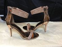 Side view of rose gold metallic, glitter rhinestone embellished high heel sandal showing ankle strap and stiletto heel.