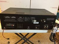 Rear view of RCA RT2770 home theater receiver showing power cord, speaker terminals, RCA audio inputs/outputs, model and specification labels.