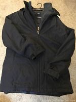 Front view of black weatherproof winter coat on hanger showing zippered front and sleeves.