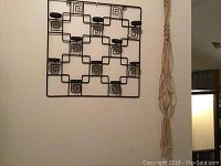 Angled view of the wrought iron candle holder on the wall, showing the thickness and dimensionality of the structure.