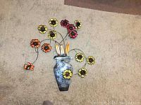 Front view of metallic flower arrangement wall hanging placed on carpet floor.