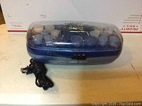 Blue Conair FastHeat hair roller set in blue heated case with rollers and clips inside, power cord visible.