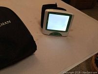 Blood pressure monitor device and storage case on table.