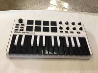 Front angle showing the full AKAI MPK Mini Pro white and black MIDI keyboard controller with keys, pads, knobs, and joystick.