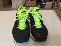 Front view of black Nike Vomero 8 sneakers with fluorescent yellow-green tongue and laces.