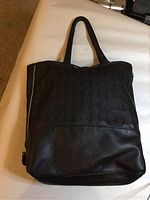 Front view of black shoulder bag showing embossed circular pattern and soft leather texture.