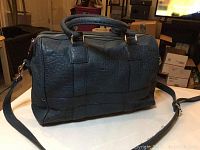 Front view of large navy blue Urban Expressions leather shoulder bag on table, showing handles and long shoulder strap.