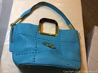 Front view of teal Michael Kors shoulder bag showing stud detailing and rectangular gold-tone handle.