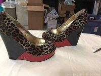 Side profile view showing leopard print upper, black wedge heel, and red platform front accent.