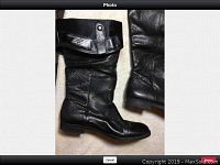 Left side view of one black leather winter boot, showing fold-over cuff and leather texture