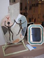 Full view of the Pietra Dura vessel with dancing figure mosaic and the adjacent marble inlaid photo frame on a shelf.