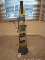 Full view of tall multicolored fused glass sculpture on painted metal stand in room.