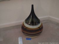 Full view of large hand blown glass vase with bulbous body and narrow neck, showing horizontal earth tone stripes.