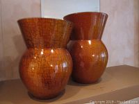Two orange-brown crackled finish vases shown side by side, each with bulbous base and flared top.