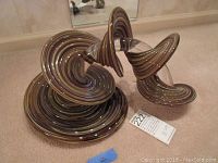 Wide view of the abstract spiral art glass sculpture on carpet showing full structure and base swirl detail.